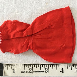 May include: A red sleeveless dress with a ruffled neckline. The dress is approximately 4 inches long.