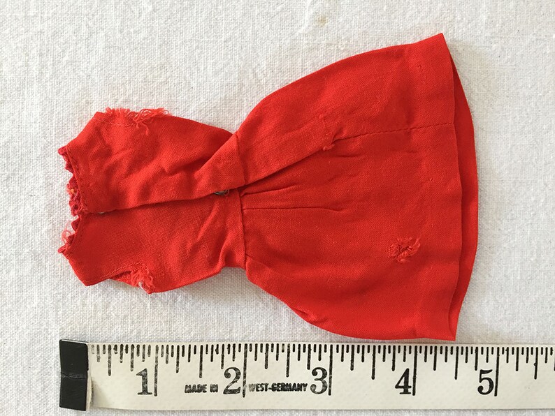 May include: A red sleeveless dress with a ruffled neckline. The dress is approximately 4 inches long.