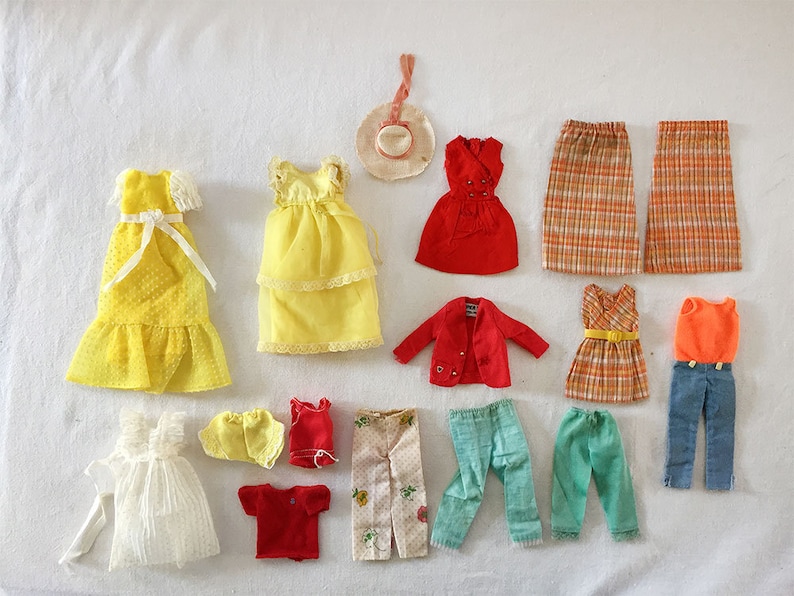 May include: A collection of vintage doll clothes, including dresses, skirts, pants, shirts, and a jacket. The clothes are in various colors, including yellow, red, orange, blue, and green. Some of the clothes have patterns, such as plaid and floral.