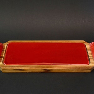 May include: A rectangular serving tray made of wood with a red ceramic insert. The tray has two red ceramic handles on either side.