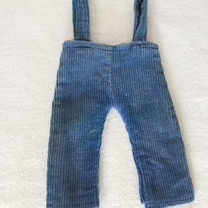 May include: Blue corduroy overalls with adjustable straps. The overalls are made of a soft, comfortable fabric and have a classic design.