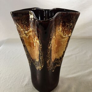 May include: A brown and gold ceramic vase with a wavy, ruffled top and a glossy finish.
