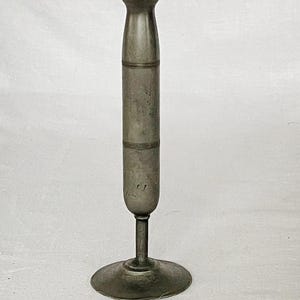 Könnte beinhalten: Eine silberne Metallvase mit einem hohen, schlanken Körper und einer ausgestellten Oberseite. Die Vase hat einen runden Boden und eine glatte, polierte Oberfläche.