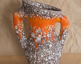 May include: A brown and white ceramic vase with orange glaze and two handles. The vase has a textured surface with small white dots.