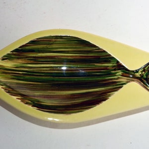 May include: A yellow ceramic dish shaped like a fish with a green and brown striped design.