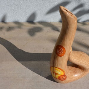 May include: A wooden vase with a unique, abstract shape and a brown, yellow, and orange swirl design.