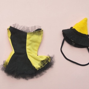 May include: A black and yellow doll dress with a black tulle skirt and a matching black witch hat with a yellow pointed top.