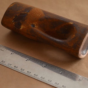 Puede incluir: Un jarr&oacute;n de cer&aacute;mica marr&oacute;n con un dise&ntilde;o abstracto &uacute;nico. El jarr&oacute;n tiene una superficie texturizada y un agujero en un lado. Mide aproximadamente 12,7 cm de largo.