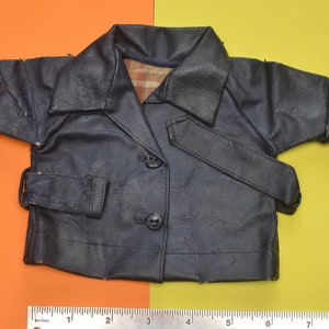 May include: A dark blue faux leather jacket with a button closure and a belt. The jacket has a plaid lining and is designed for a child.
