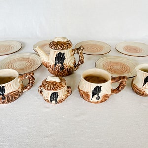 Op de afbeelding: Een bruin en wit keramisch theeservies met een boomstamontwerp. De set bevat een theepot, een suikerpot, een roomkan, twee kopjes en zes schoteltjes.