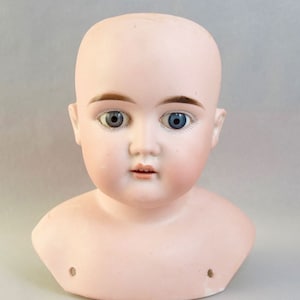 以下が含まれることがあります： 青い目と描かれた眉毛を持つ、磁器製のドールヘッド。頭部は磁器製の胸像に付けられています。