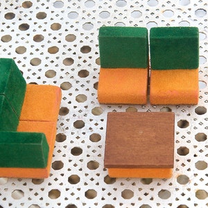 Op de afbeelding: Een miniatuur woonkamerset met een groene en oranje bank, twee groene en oranje stoelen en een bruine en oranje salontafel. De set is gemaakt van hout en stof.
