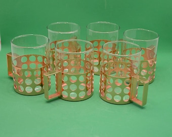 May include: Set of six clear glass mugs with gold metal handles and a gold metal band around the middle of each mug. The band has a pattern of small circles.