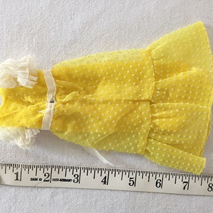May include: A yellow polka dot dress with white lace trim. The dress is about 7 inches long.
