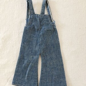 May include: A pair of blue denim dungarees with wide legs and adjustable straps.