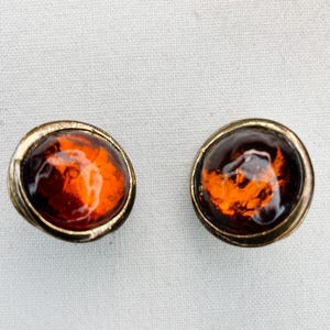 May include: A pair of gold tone earrings with amber colored glass stones.