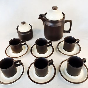 May include: A brown and white ceramic coffee set with a teapot, creamer, and six cups and saucers.