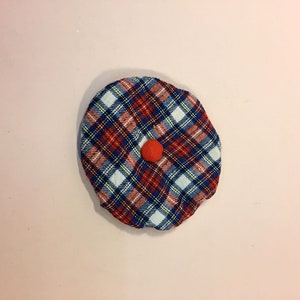 Könnte beinhalten: Eine rote, blaue und weiße karierte Stoffmütze mit einem roten Bommel oben.