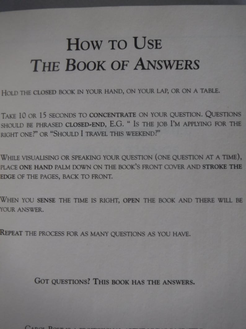 K&ouml;nnte beinhalten: Eine Seite aus "The Book of Answers" mit Anweisungen. Der Text erkl&auml;rt, wie man eine Frage stellt, die Seiten streicht und das Buch &ouml;ffnet, um eine Antwort zu erhalten. Der Titel ist fett gedruckt und in einer Serifenschrift.