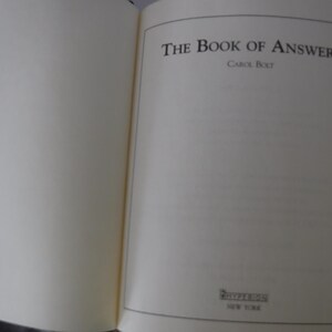 K&ouml;nnte beinhalten: Ein aufgeschlagenes Buch mit dem Titel "The Book of Answers" in schwarzer Schrift. Der Name des Autors, Carol Bolt, steht darunter. Der Verlag Riverhead ist ebenfalls zu sehen, mit "New York" darunter. Die Seiten sind cremefarben.