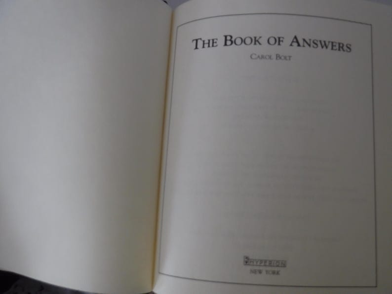 K&ouml;nnte beinhalten: Ein aufgeschlagenes Buch mit dem Titel "The Book of Answers" in schwarzer Schrift. Der Name des Autors, Carol Bolt, steht darunter. Der Verlag Riverhead ist ebenfalls zu sehen, mit "New York" darunter. Die Seiten sind cremefarben.