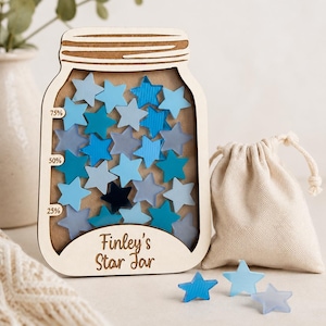 May include: A wooden star jar in the shape of a mason jar, filled with blue star tokens. The jar features the text "Finley's Star Jar" and percentage markers. A small drawstring bag and extra stars are placed beside the jar.