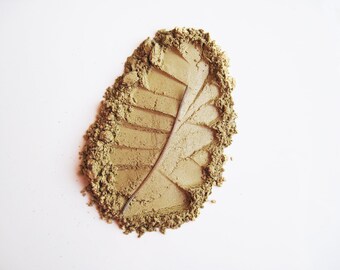 May include: A green powder in the shape of a leaf, with a leaf-shaped impression in the center.