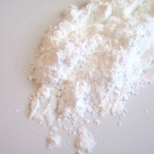 May include: A close-up of a pile of white powder, likely cornstarch or powdered sugar, on a white surface.