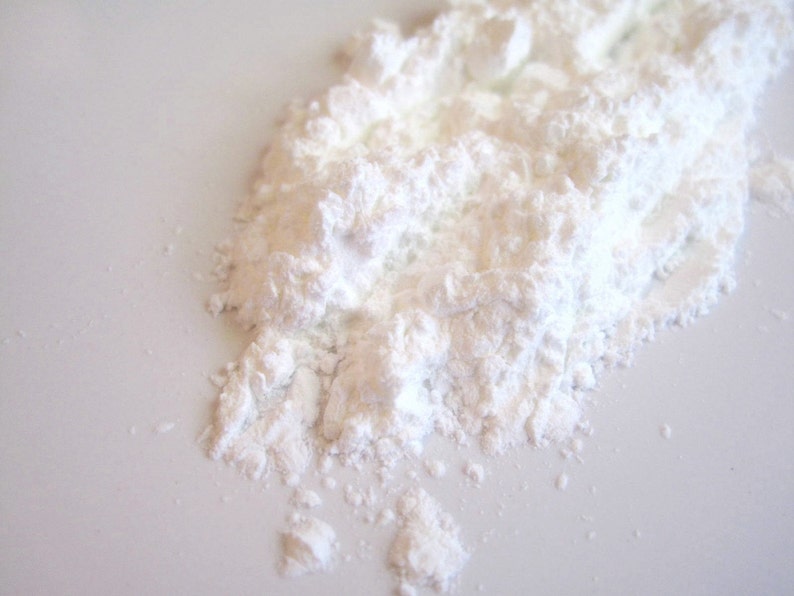May include: A close-up of a pile of white powder, likely cornstarch or powdered sugar, on a white surface.