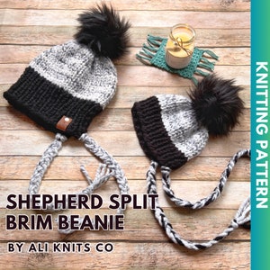 Op de afbeelding: Twee zwart-witte gebreide mutsen met zwarte pompoenen en lange zwart-witte gevlochten banden. De mutsen hebben een gespleten rand en liggen op een houten oppervlak. De tekst "SHEPHERD SPLIT BRIM BEANIE BY ALI KNITS CO" staat onder de mutsen.