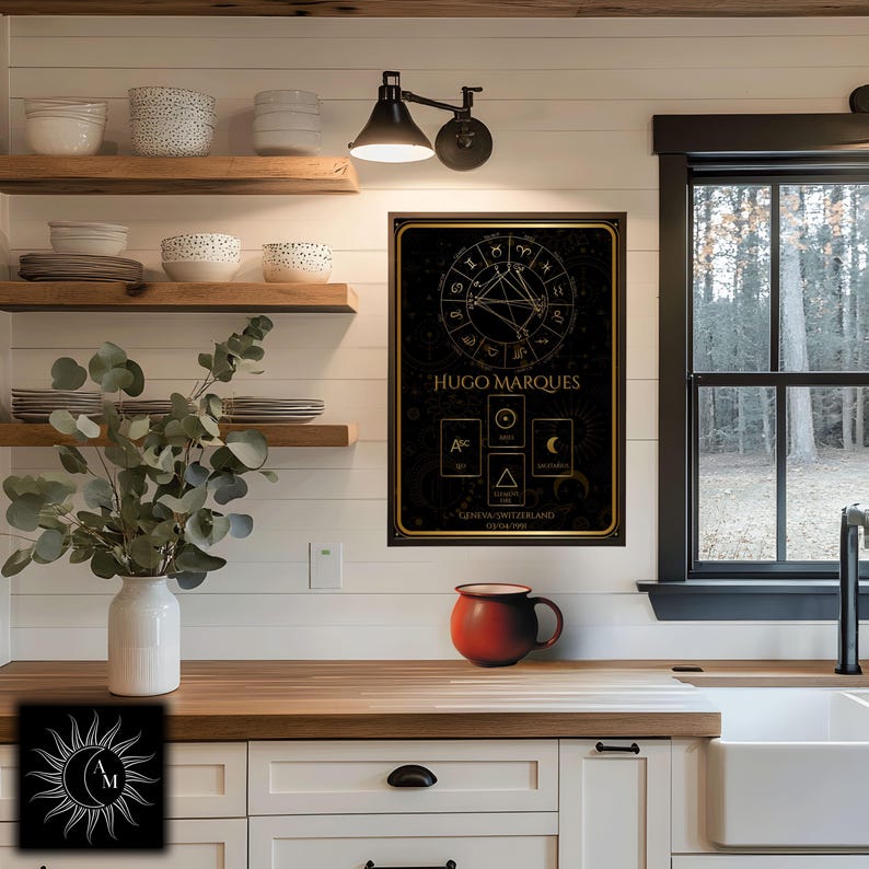 Peut inclure: Une affiche encadr&eacute;e noire et dor&eacute;e avec des symboles astrologiques et le nom "HUGO MARQUES". L'affiche est accroch&eacute;e &agrave; un mur blanc au-dessus d'un comptoir en bois. Une tasse rouge est pos&eacute;e sur le comptoir.