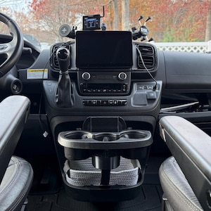 Peut inclure: Intérieur du tableau de bord d'un véhicule, avec volant, écran d'infodivertissement et commandes. Le tableau de bord noir a des accents argentés, des porte-gobelets et des rangements. Sièges gris foncé. Intérieur de véhicule moderne.