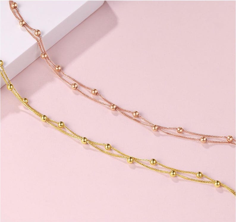 Two 18K rose gold Starry Sky bracelets layered on pink background