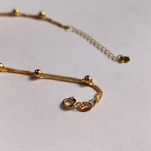 Close up of 18K gold Chopin chain starry sky bead and heart clasp detail
