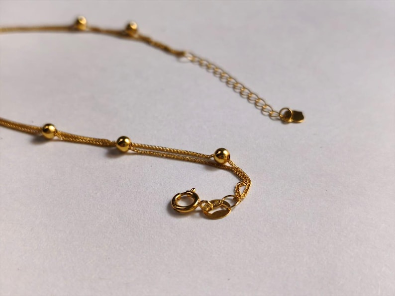Close up of 18K gold Chopin chain starry sky bead and heart clasp detail