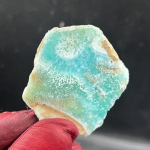 May include: A flat, irregularly shaped slab of polished mineral featuring a vibrant turquoise and mint green color palette. The surface displays intricate, radiating white crystalline patterns and natural beige inclusions along the edges.