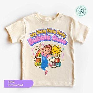 May include: A cream-colored t-shirt featuring a colorful graphic. The graphic includes the text "Icky Sticky Sticky Sticky Bubble Gum" in pink and blue, a cartoon girl, a rainbow, a smiling sun, and ABC and 123 blocks. The shirt is a children's apparel item.