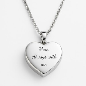 May include: A silver heart pendant necklace. The pendant is engraved with the words "Mum Always with me" in black script. The necklace chain is silver and attached to the pendant.
