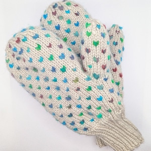 May include: A pair of beige knitted mittens with a colourful heart pattern in blue, green, and burgundy. The mittens are made of a thick yarn and have a ribbed cuff.