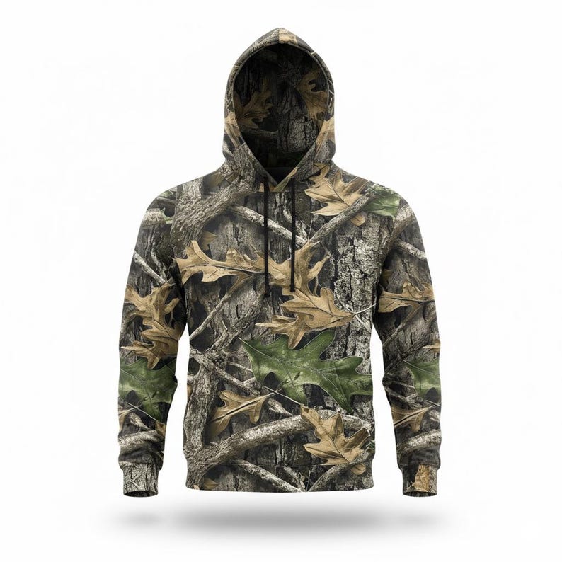 Puede incluir: Una sudadera con capucha de camuflaje con un patr&oacute;n de hojas de roble y corteza de &aacute;rbol marrones, verdes y beiges. La parte superior de manga larga tiene una capucha con cord&oacute;n y pu&ntilde;os acanalados.