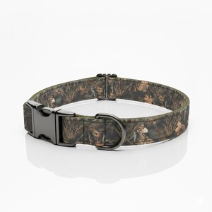 May include: Camouflage dog collar with a black metal buckle and D-ring. The collar features a pattern of brown, green, and tan leaves and foliage. The collar is designed for medium to large dogs.