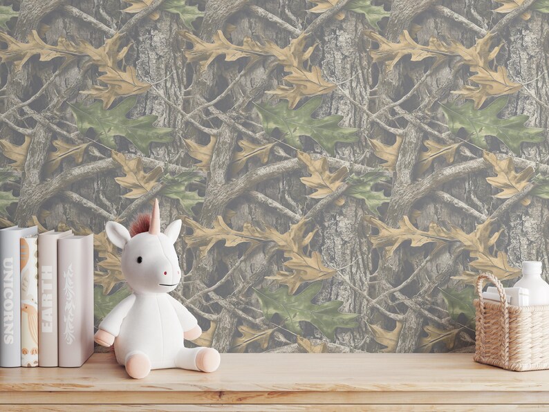 Puede incluir: Un unicornio de peluche blanco con cuerno y pezu&ntilde;as rosas est&aacute; sobre una superficie de madera. Detr&aacute;s hay varios libros con t&iacute;tulos como "UNICORNS" y "EARTH". El fondo presenta un patr&oacute;n de camuflaje marr&oacute;n, verde y beige.