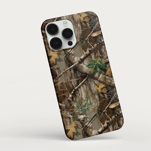 May include: A phone case featuring a camouflage pattern with brown, green, and tan hues. The design includes branches, leaves, and a textured appearance, providing a natural, outdoorsy aesthetic. The case has a camera cutout.