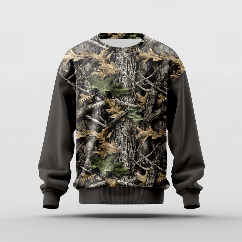 Puede incluir: Sudadera de cuello redondo con un dise&ntilde;o de camuflaje de corteza de &aacute;rbol y hojas en tonos marr&oacute;n, verde y gris. Las mangas son de color gris oscuro liso, y la sudadera tiene un dobladillo y pu&ntilde;os de canal&eacute;. Adecuada para actividades al aire libre.