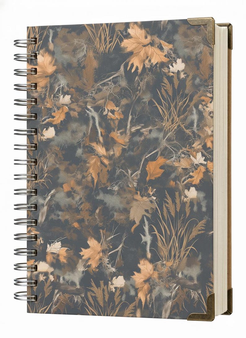 May include: Spiral-bound notebook with a camouflage pattern of autumn leaves in shades of brown, tan, and gray. The notebook has a dark gray background and metal corner protectors. The pages are cream-colored.