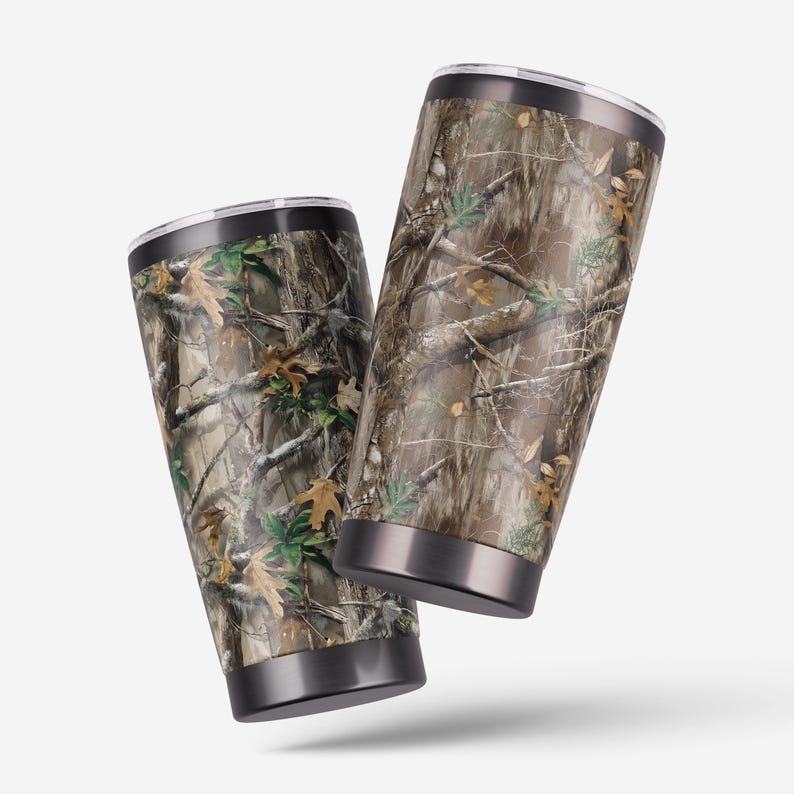 May include: Two stainless steel tumblers with a camouflage pattern. The tumblers have a black rim and base, and a silver lid. The camouflage design features brown, green, and tan colors, mimicking a forest environment.