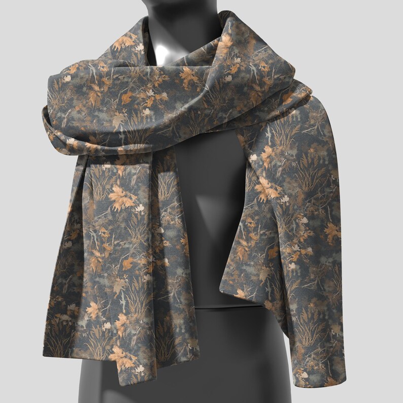 May include: A dark gray scarf with a repeating pattern of tan and brown leaves and foliage. The scarf is draped over a mannequin, showcasing its design and texture. The scarf appears to be made of a soft, flowing fabric.