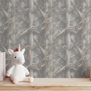 May include: A white unicorn plush toy with a pink horn and hooves sits on a wooden surface. Behind it is a backdrop of a gray and brown tree pattern. Books and a small basket are also on the surface.
