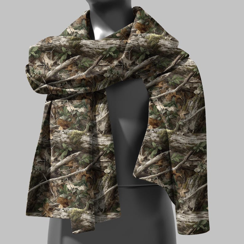 Puede incluir: Bufanda de camuflaje con un patr&oacute;n forestal realista. El dise&ntilde;o presenta corteza de &aacute;rbol marr&oacute;n, hojas verdes y ramas, creando una est&eacute;tica natural al aire libre. La bufanda est&aacute; drapeada sobre un maniqu&iacute;.