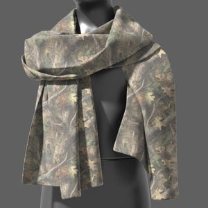 May include: A camouflage-patterned scarf draped over a mannequin. The scarf features a mix of brown, green, and tan hues, with a detailed print of leaves and branches. The fabric is soft and appears to be lightweight.